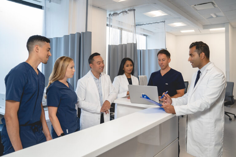 Sorin Medical Group team gather around a desk looking at a computer and medical files.